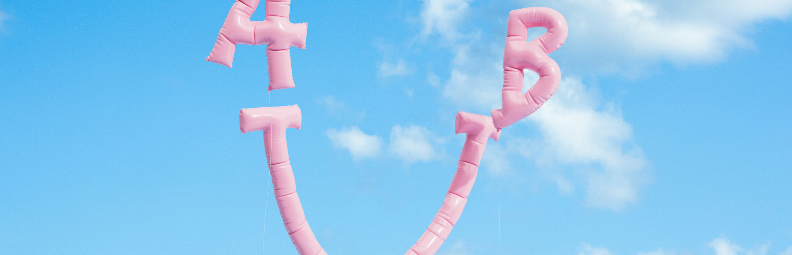 Un frisbee rosa con pegatinas de Incharge volando a través de un cielo azul claro.